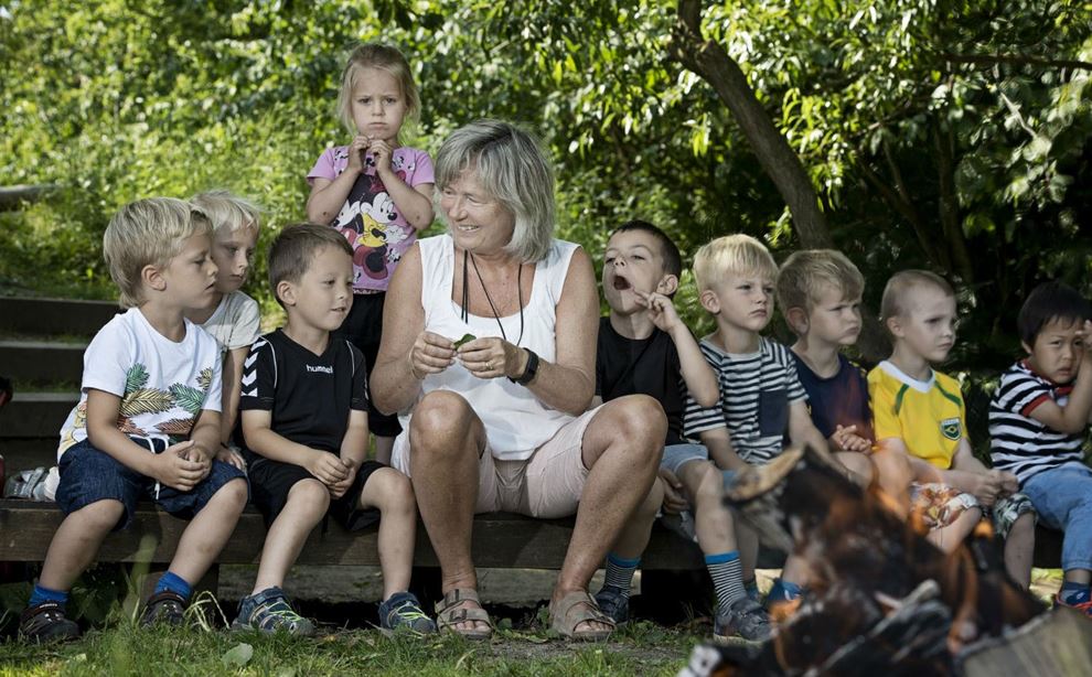 Lene Pedersen pædagogmedhjælper sidder sammen med en gruppe børnehavebørn
