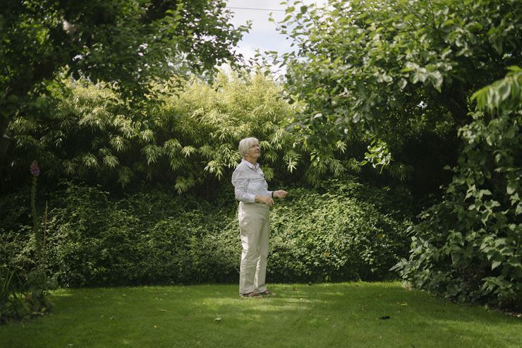 En kvinde står i en have og kigger på træer og buske