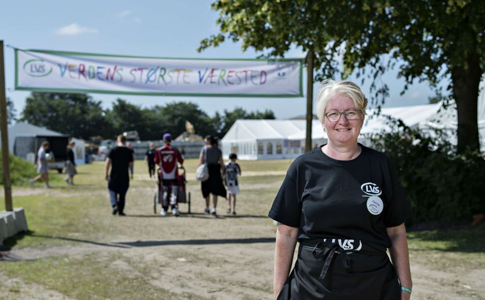 Pædagogmedhjælper Cathe foran skiltet til Ferie Camp 2019 i Randers. 