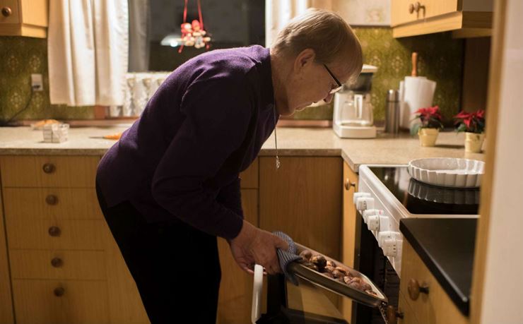 En ældre kvinde tager æbleskiver ud af ovnen